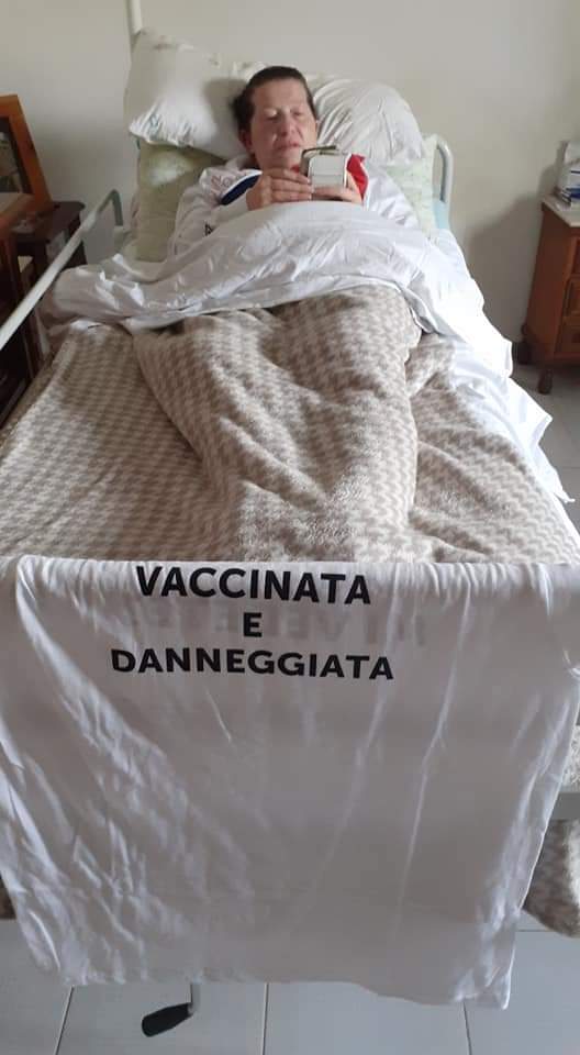 la signora Rosaria con la maglietta "vaccinata e danneggiata" che pende dal letto