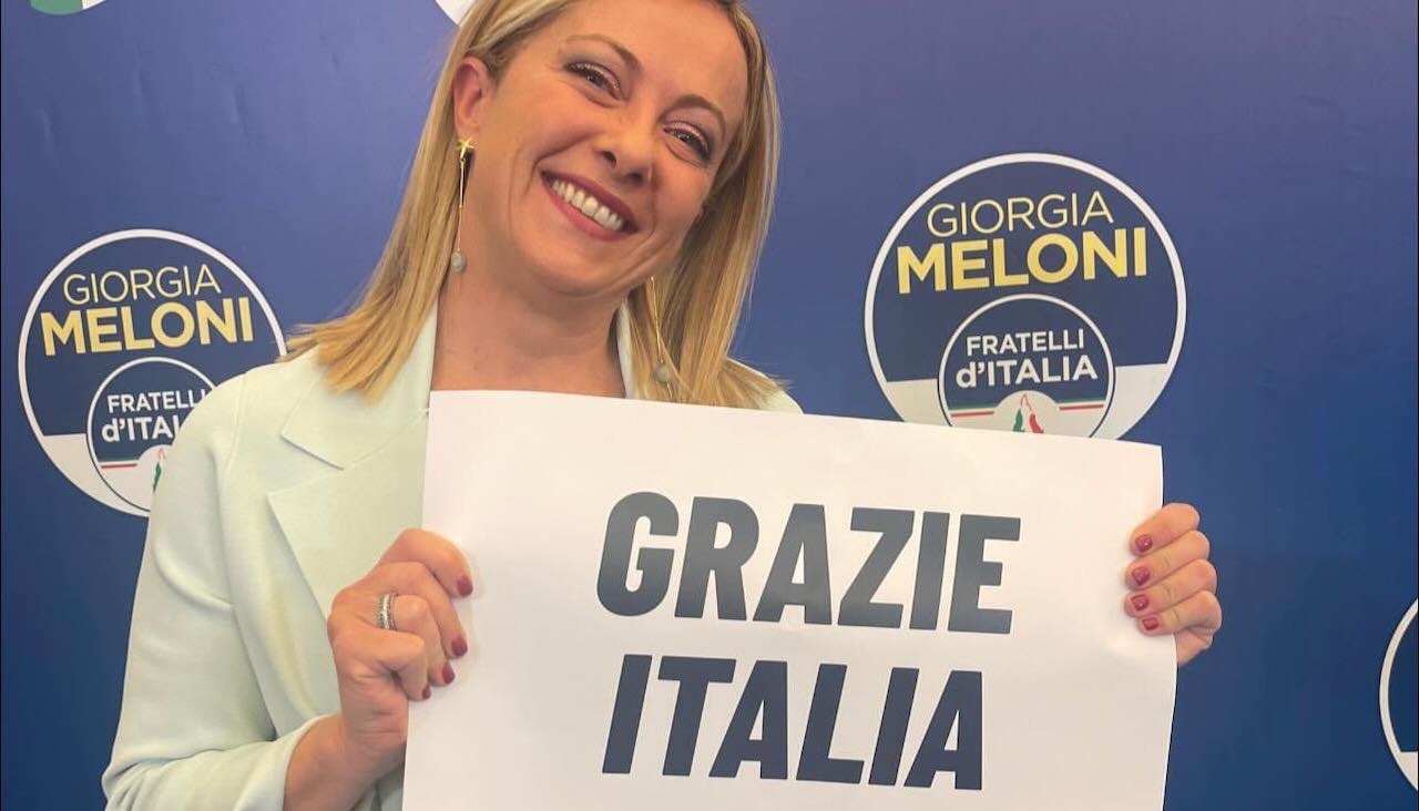 Giorgia Meloni che tiene un cartello con scritto "grazie italia"